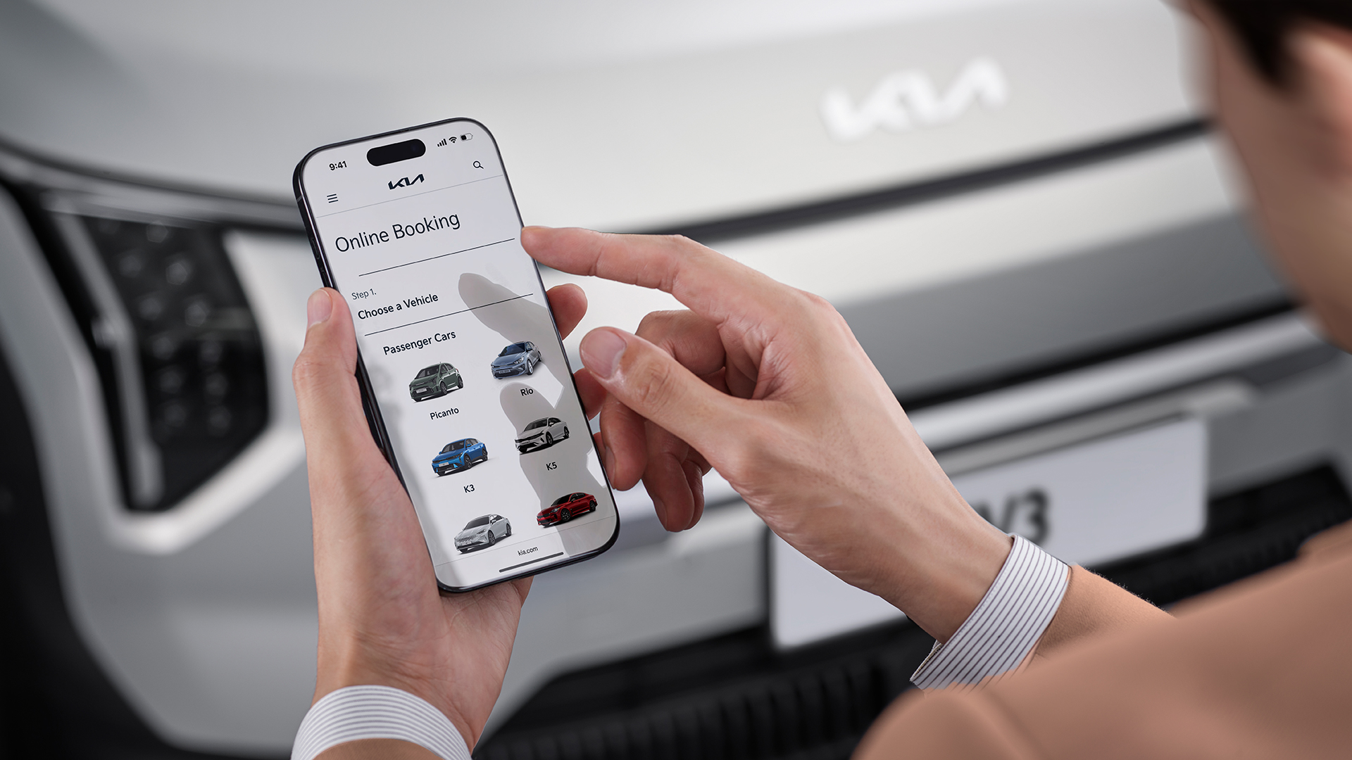 شخص يستخدم هاتفًا ذكيًا أمام سيارة Kia EV3