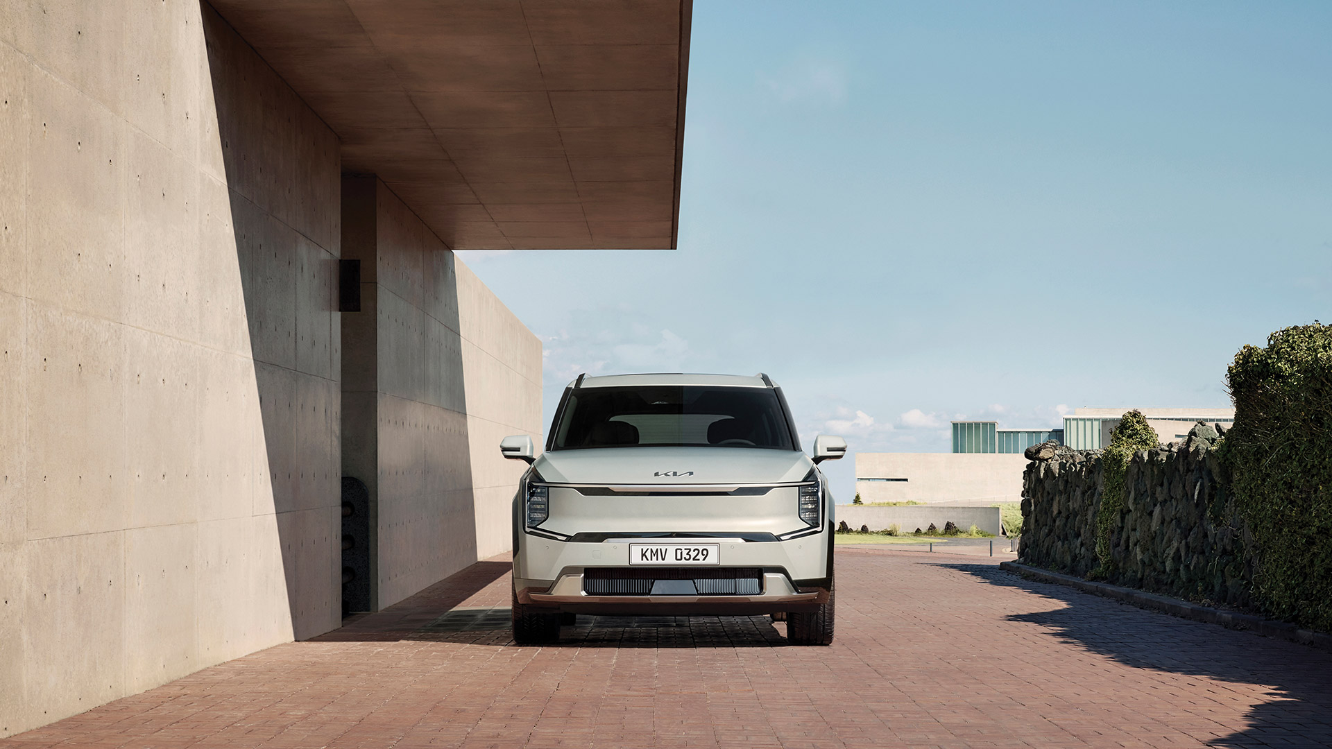 Front view of EV9 parked next to a high wall