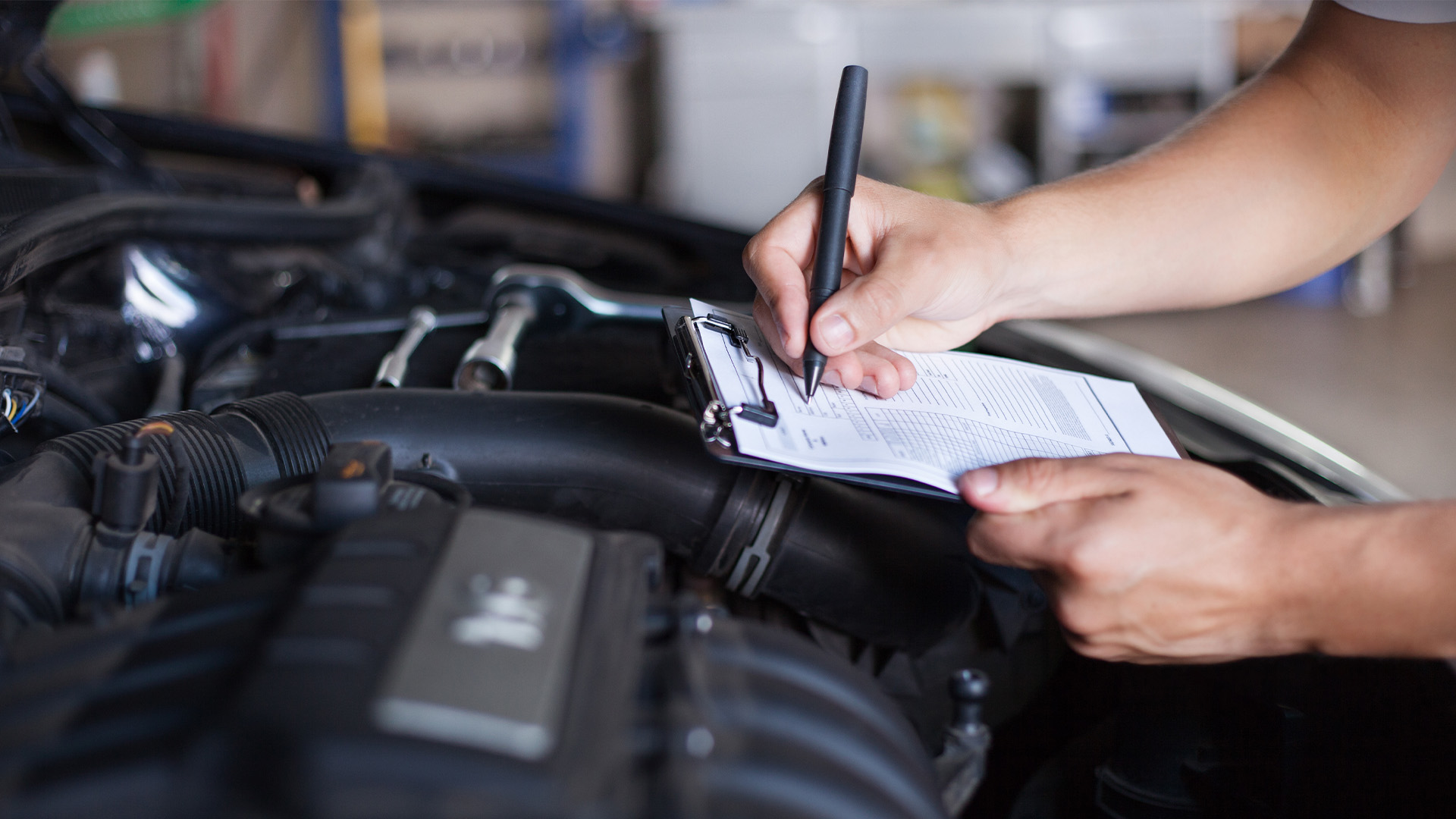 Mechanic marking checklist on a open bonnet