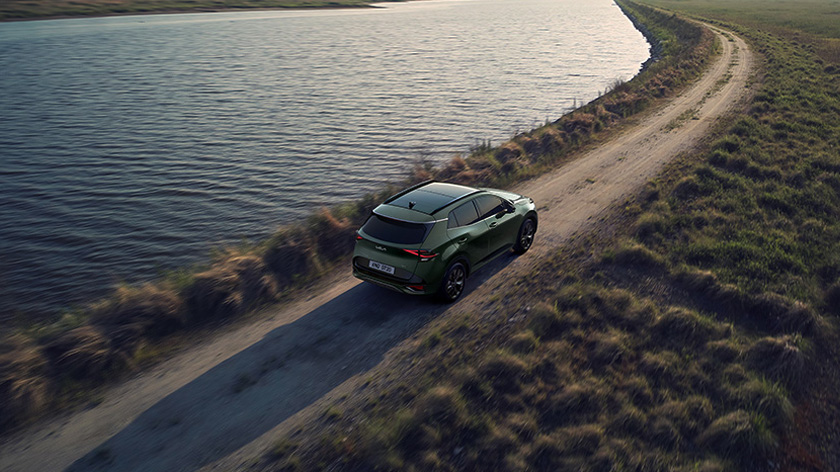 Wide view of the Sportage speeding in nature with views of rivers and mountains