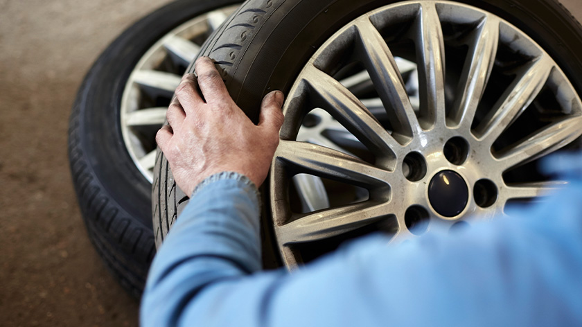 Man trying to lift one of the tires on the floor