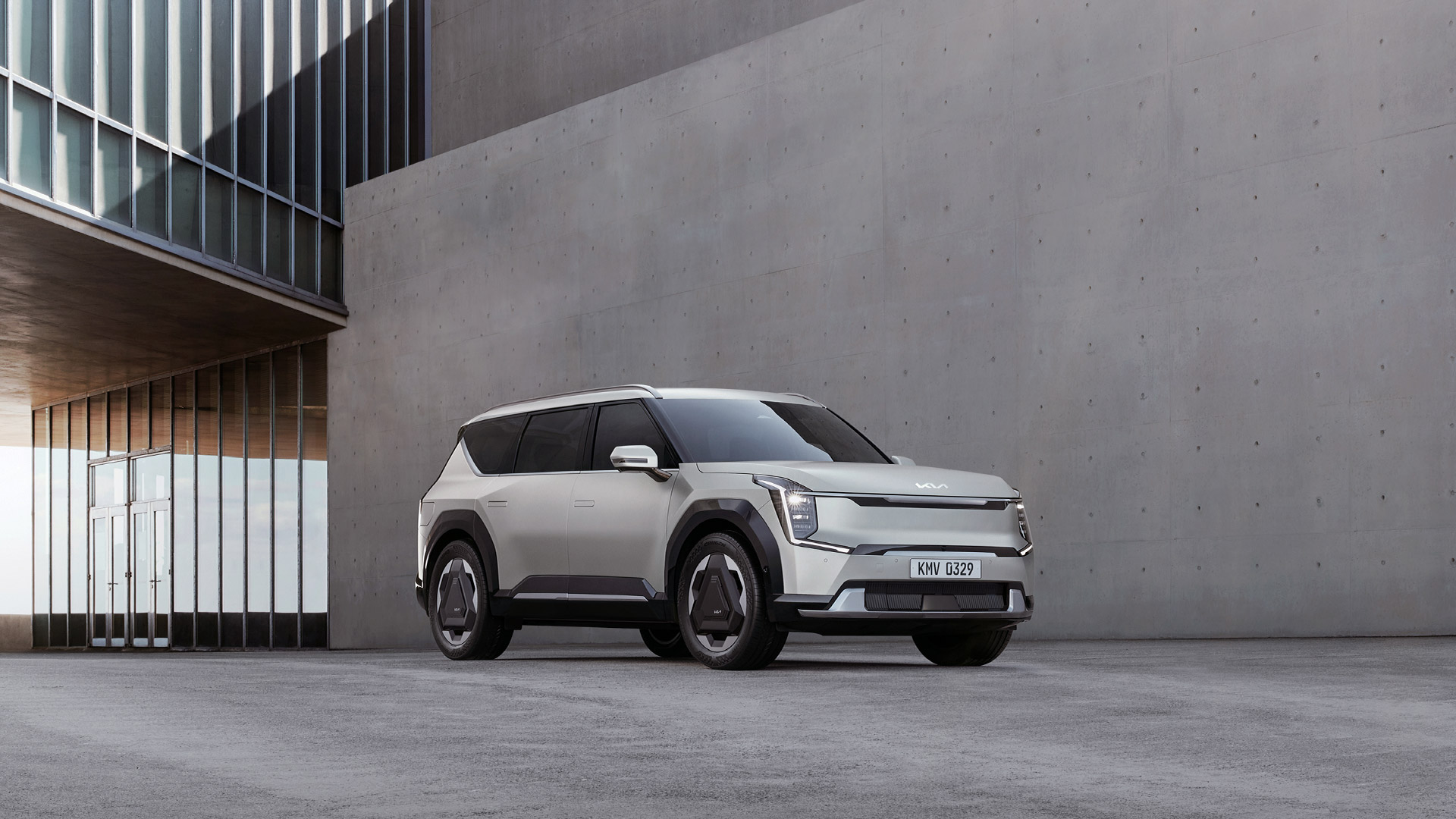 Front side view of Kia EV9 parked in front of a high wall